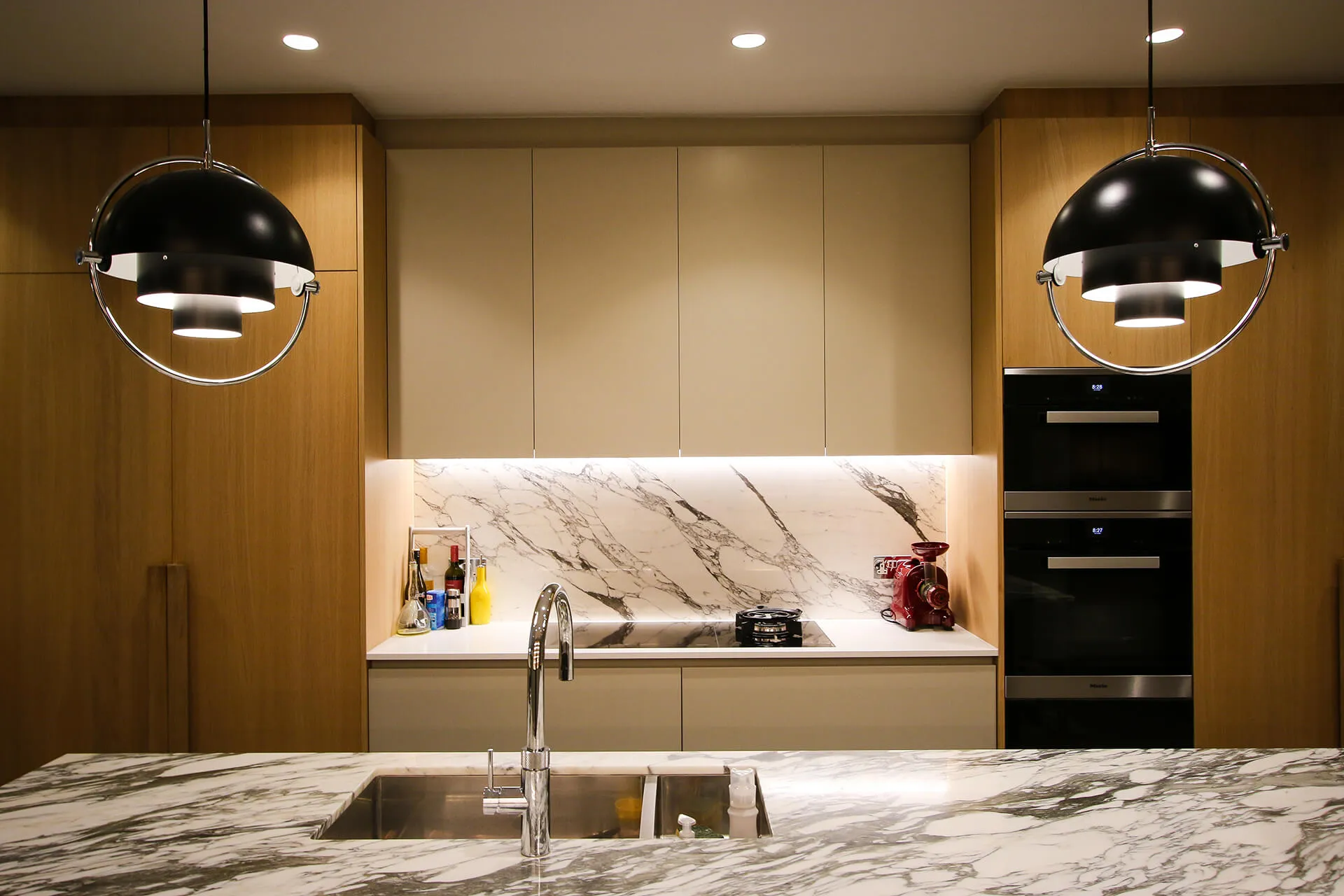 Modern kitchen featuring a marble countertop, sleek cabinetry, and stylish pendant lighting above the sink and cooktop.